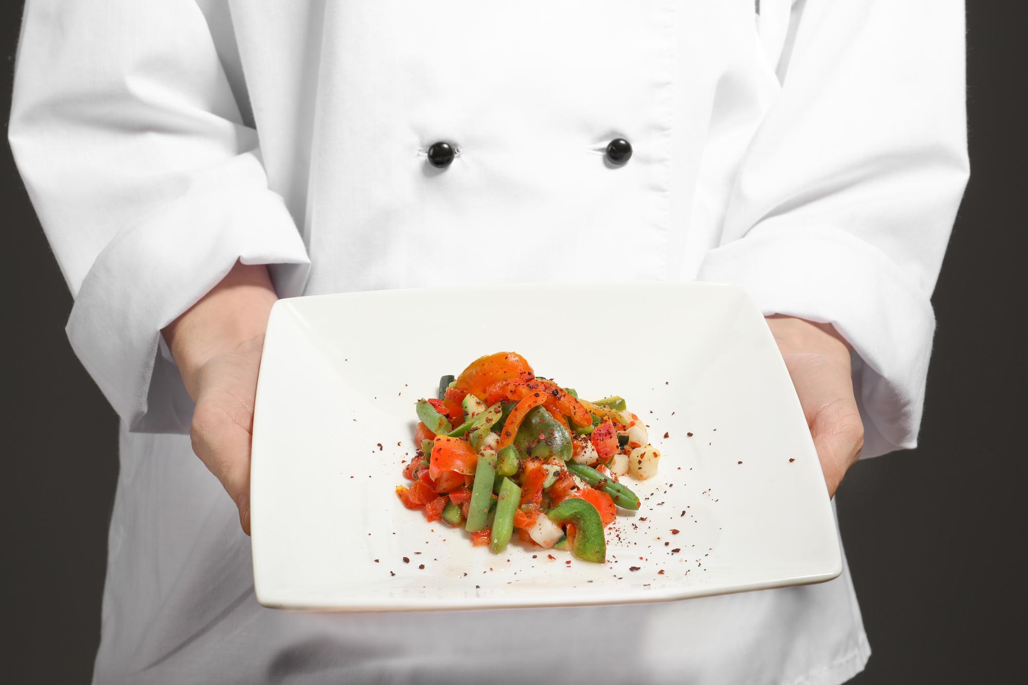 Chef demonstrating plating technique in a modern kitchen